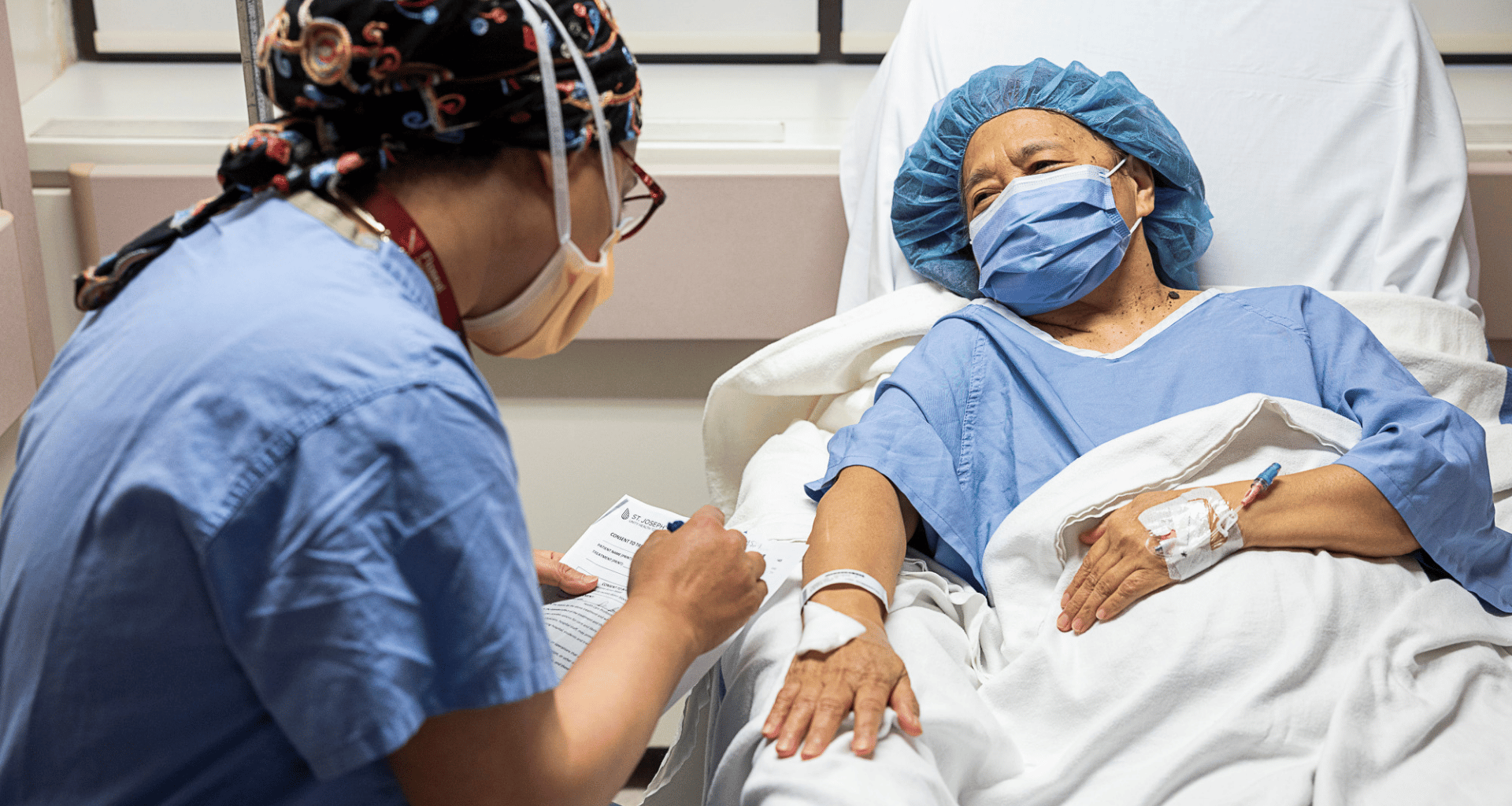Doctor by a patient's bedside writing on a notepad