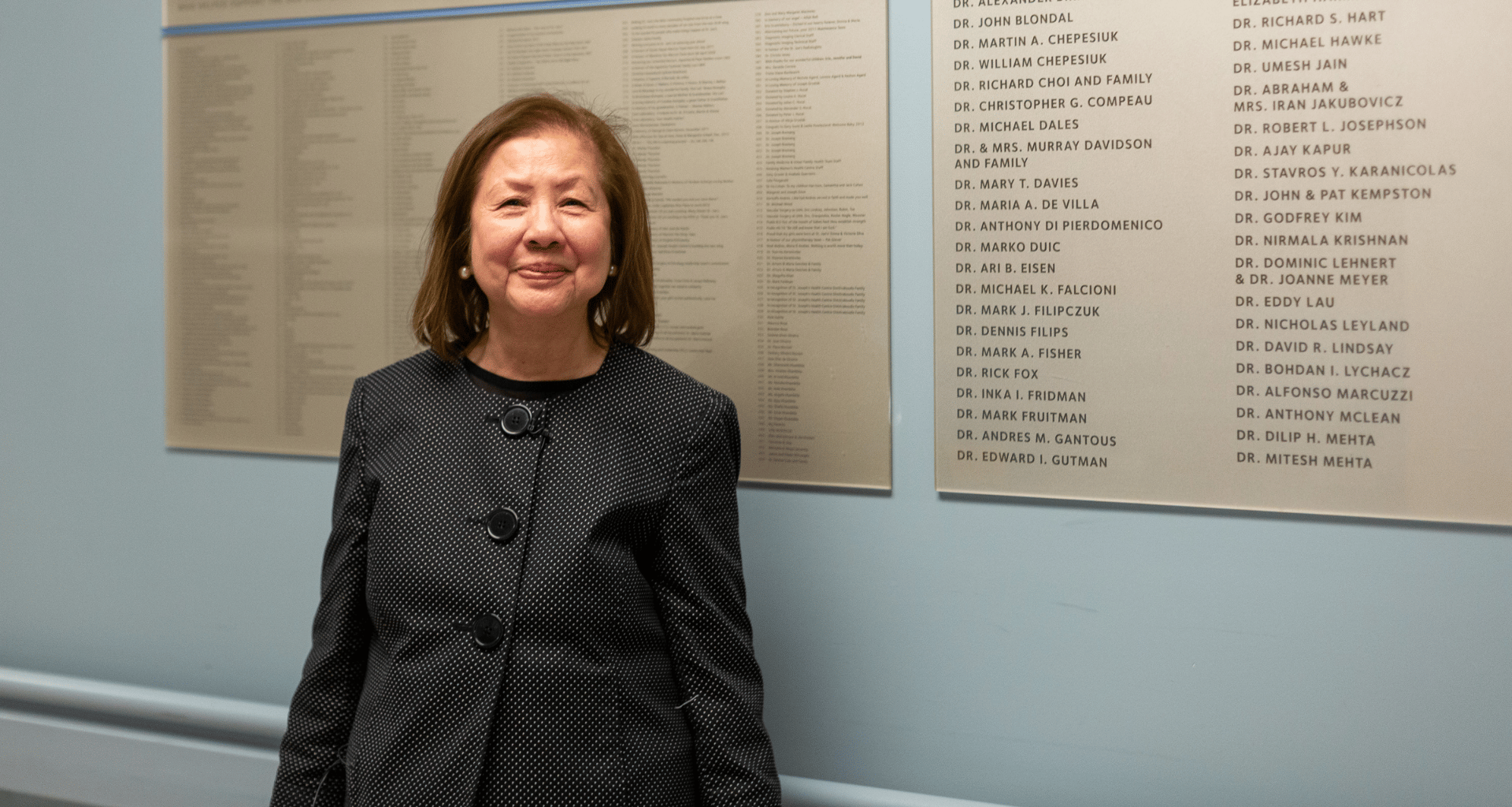 Dr. Maria De Villa standing in front of the donor wall at St. Joe's